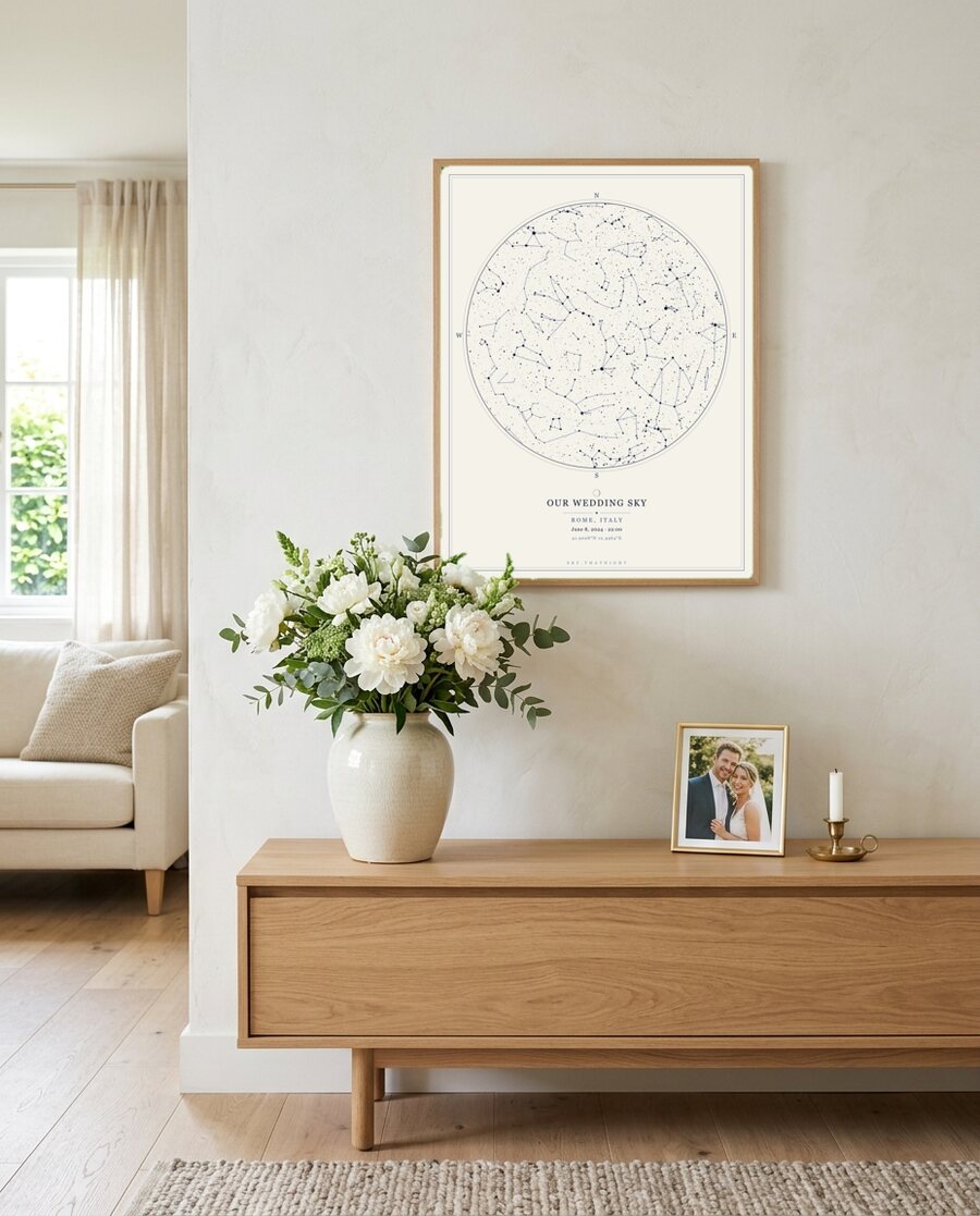 Framed star map above a console with wedding flowers